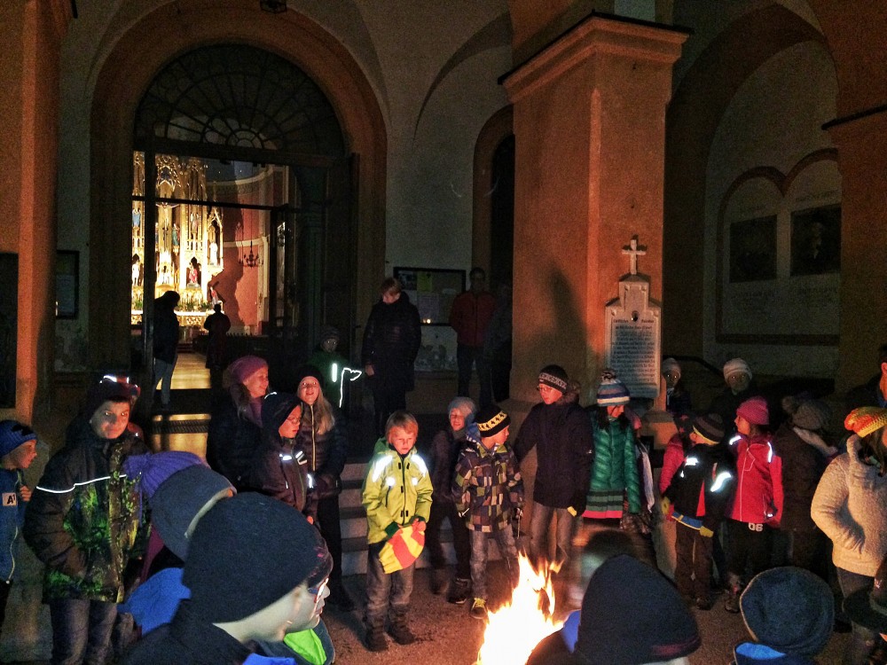 Kinder wärmen sich am offenen Feuer vor der Zirler Pfarrkirche