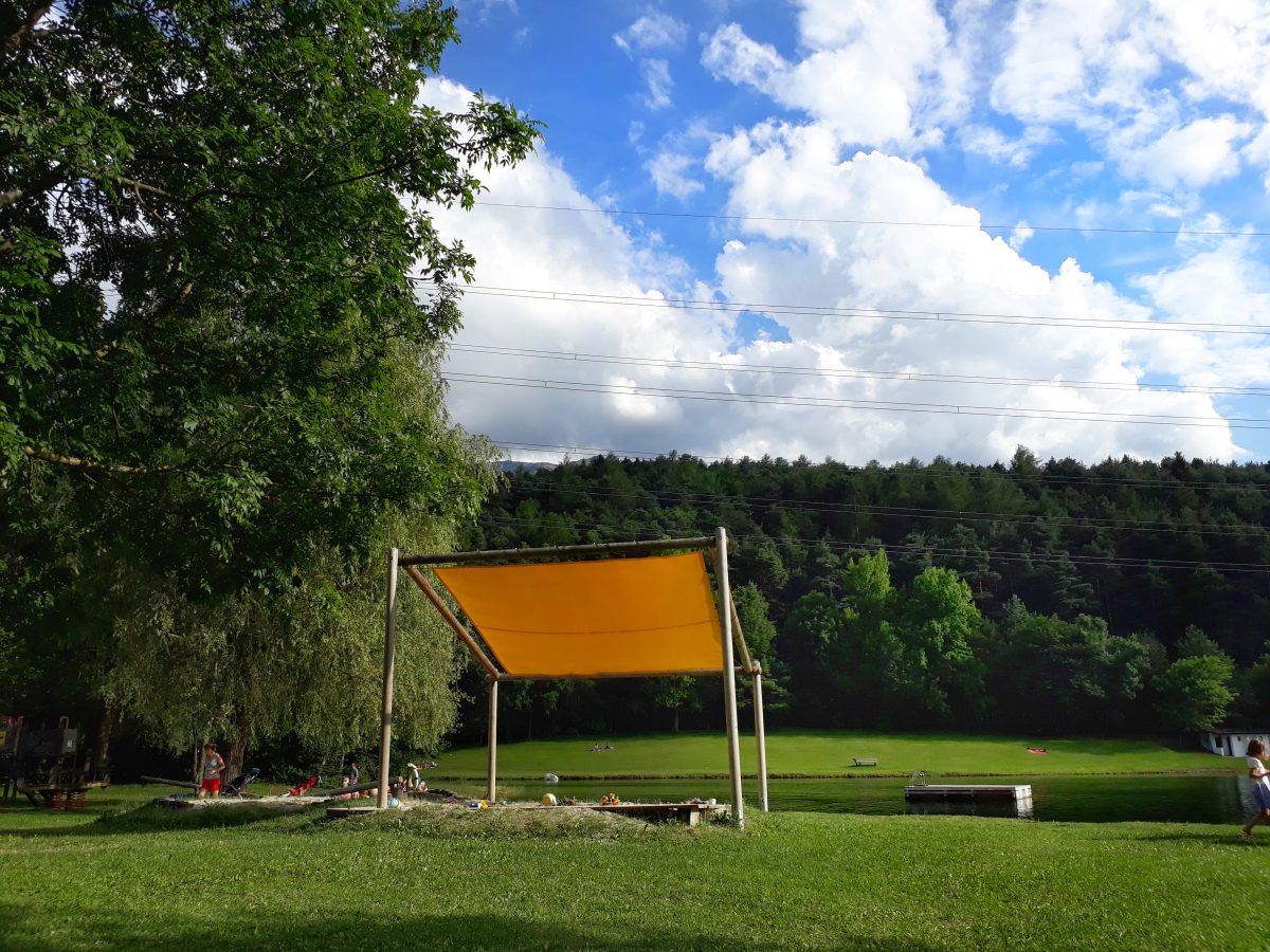 Ein Sonnensegel schützt die spielenden Kinder in der Sandkiste vor der Hitze.