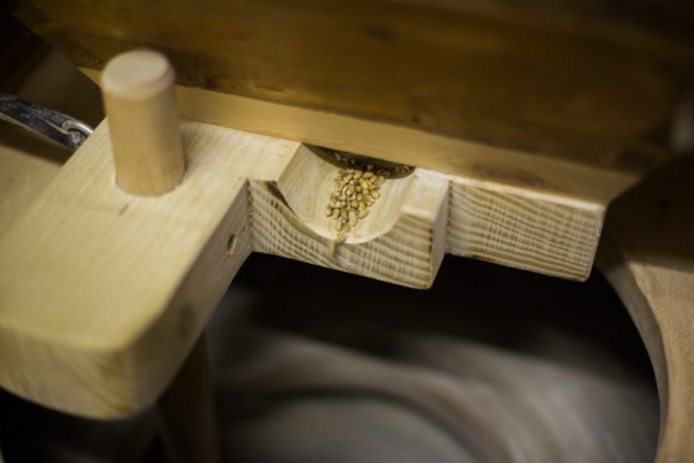 Hier rieselt das Korn langsam auf den Mahlstein hinunter.