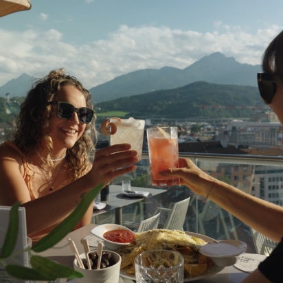 Two people drinking cocktails on a rooftop bar in Innsbruck