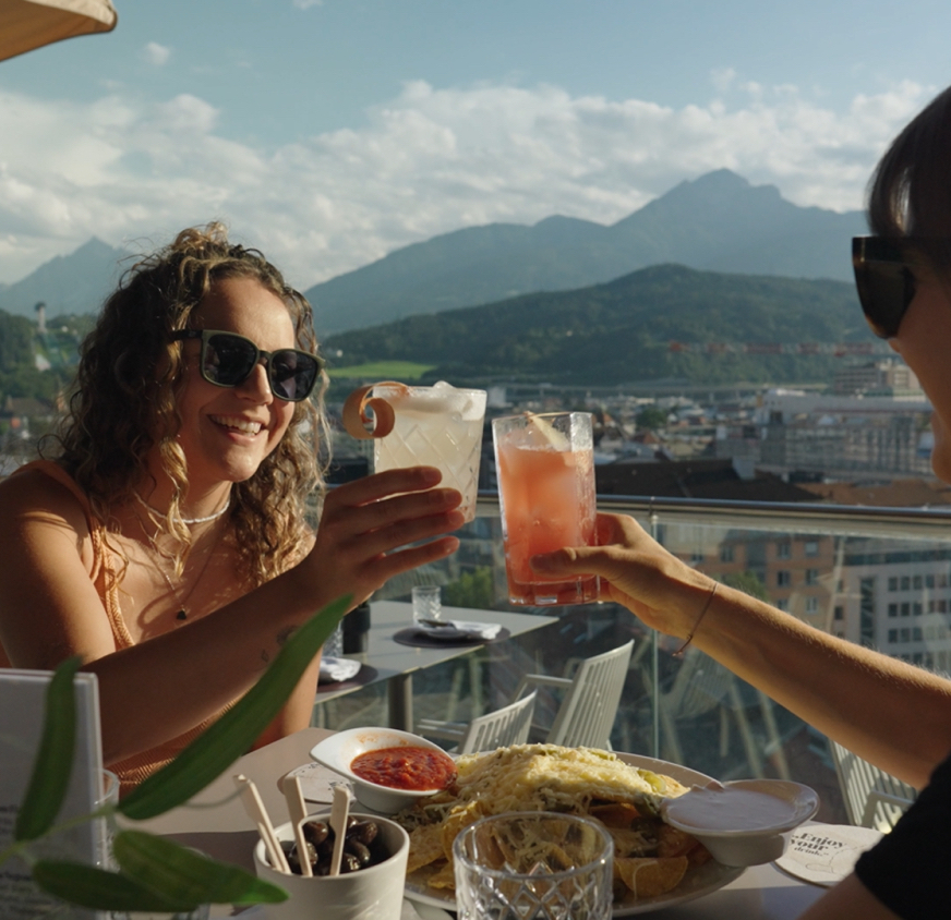 Two people drinking cocktails on a rooftop bar in Innsbruck